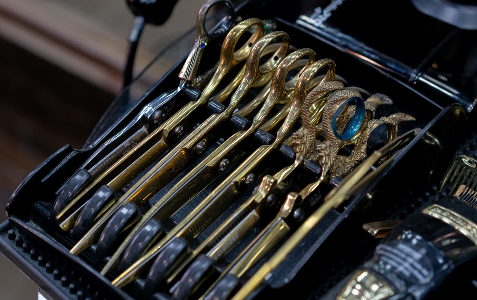 Gold barber scissors lined up in a tray at the shop